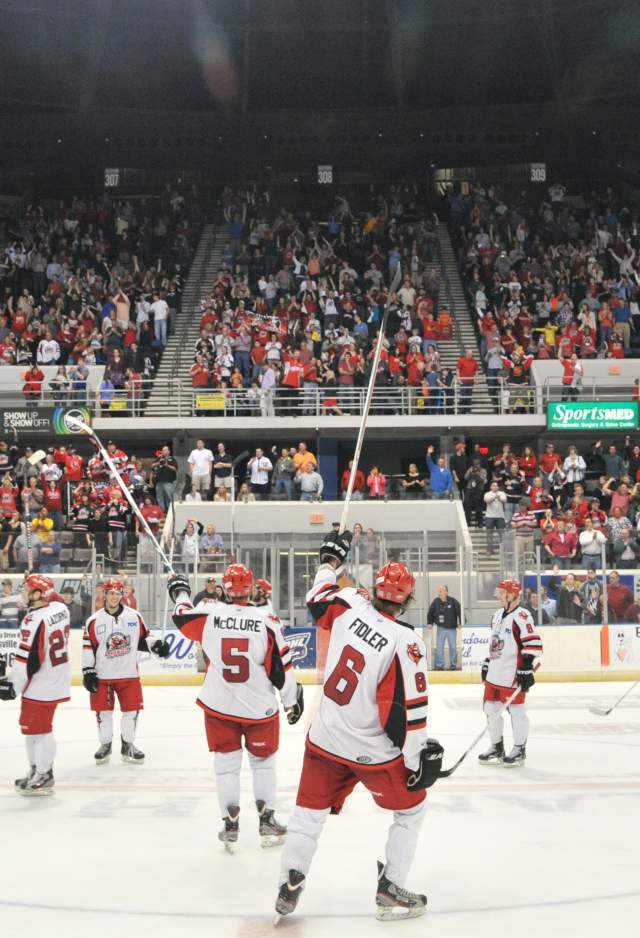 Huntsville Havoc hockey game with fans in red and white cheering from stadium stands.