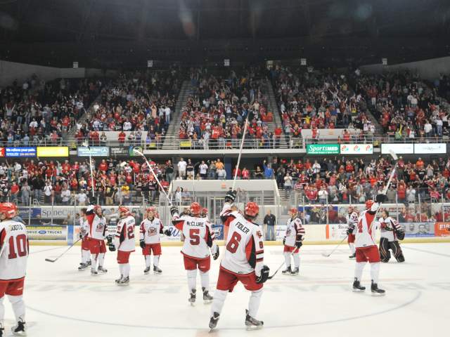 Huntsville Havoc hockey game with fans in red and white cheering from stadium stands.