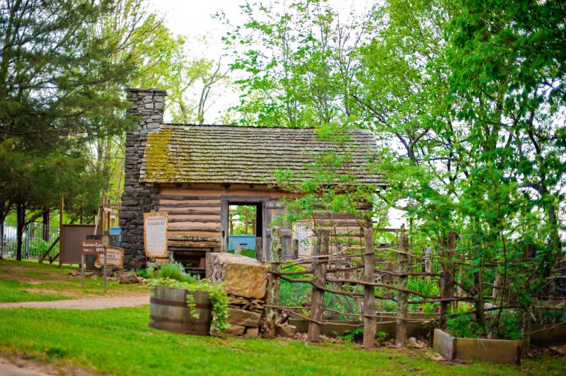 Restored log cabin surrounded by greenery at a historic site in Huntsville