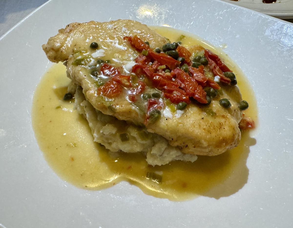 Plated chicken dish with sun-dried tomatoes and sauce at a local restaurant in Huntsville, Alabama.