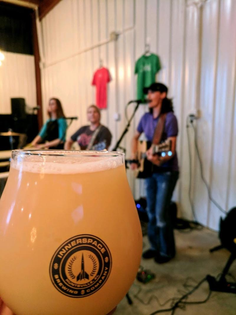 A beer held by a patron while watching a live band perform at Innerspace Brewing