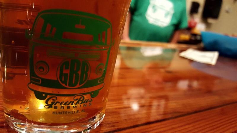 A beer in a branded glass from Green Bus Brewing in Huntsville, AL