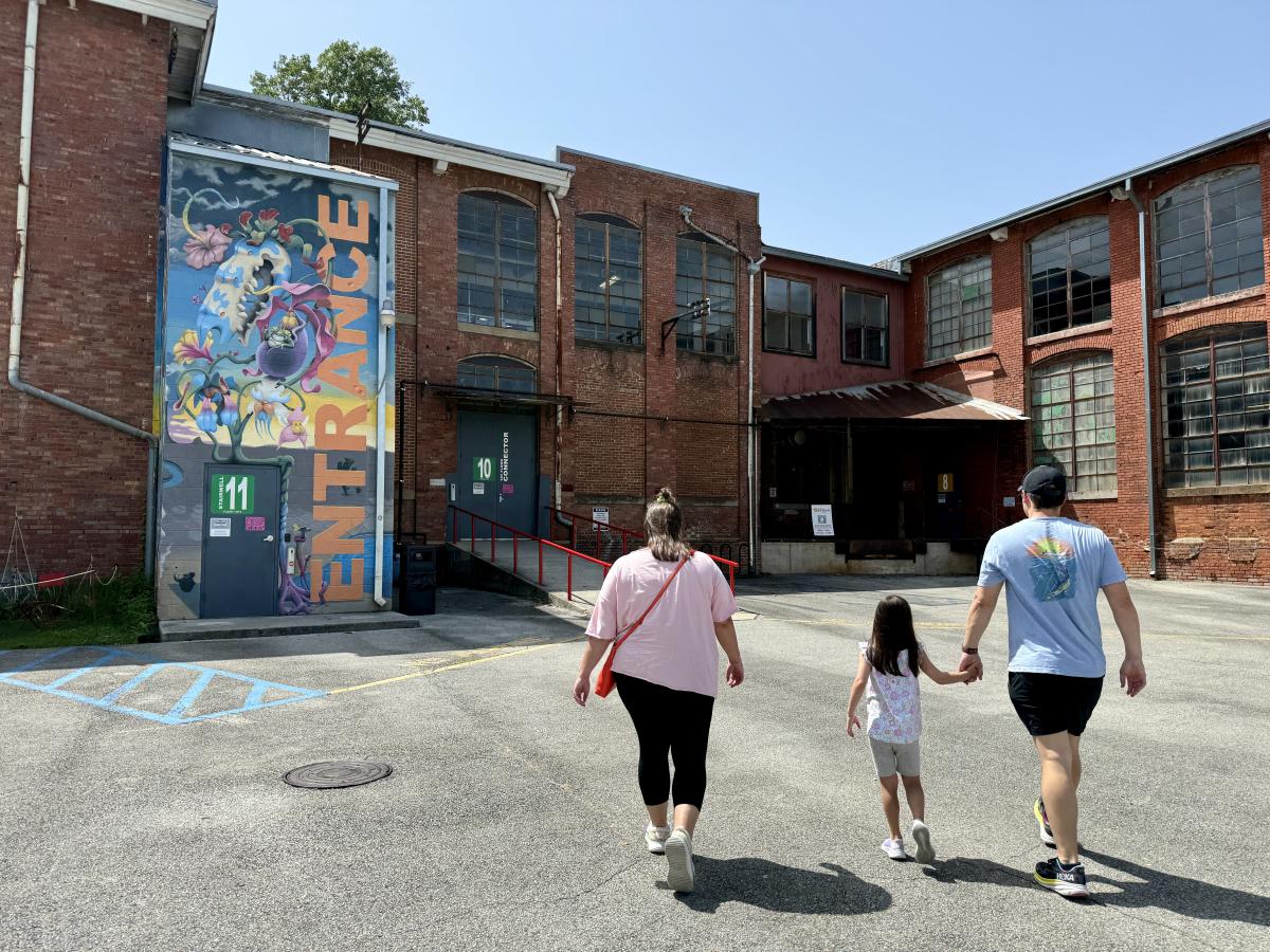 Family walking toward Lowe Mill ARTS & Entertainment, a historic arts complex in Huntsville, Alabama.